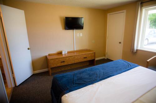 伊利Steelhead Inn的卧室配有一张床,墙上配有电视。