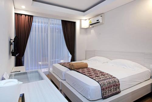 登巴萨彭多克奈曼15号旅馆的一间卧室设有一张大床和一张玻璃桌