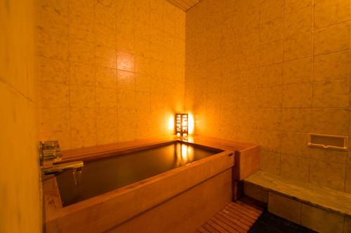 指宿市秀水园日式旅馆的带浴缸的浴室,墙上有灯