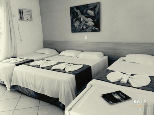 朱奎Pousada Hippocampus的酒店客房内的三张床,配有白色床单