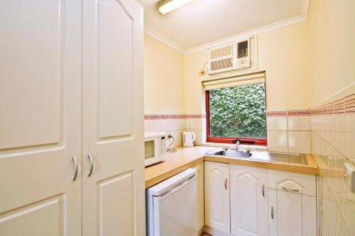 洛恩洛恩车夫客栈的厨房配有白色橱柜、水槽和窗户。
