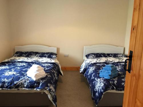 阿基尔High Road Cottage的一间卧室配有两张带蓝白色床单的床