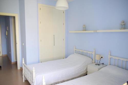 罗塔Apartamento Costa Ballena con WIFI的卧室设有两张单人床和蓝色的墙壁