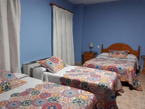 特鲁希略胡里奥旅馆的一间卧室设有两张床,拥有蓝色的墙壁。