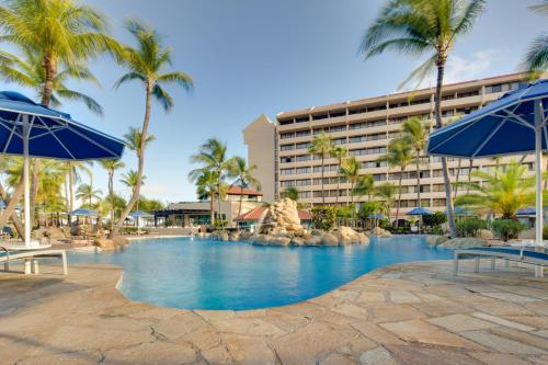 棕榈滩巴塞罗阿鲁巴全包度假酒店的一座拥有棕榈树和蓝伞的度假游泳池