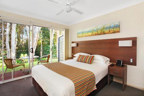 麦夸里港菲林冲浪海滩别墅酒店的一间带大床的卧室和一个阳台