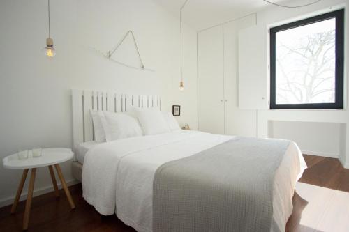 埃武拉Casa dos Aromas的白色的卧室设有白色的床和窗户。