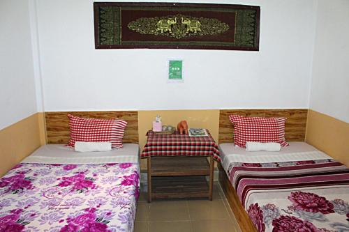 Kampong Chhnang加登旅馆的一间设有两张床和一张桌子的房间