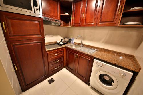 阿吉曼中城家具公寓的一间带木制橱柜和洗衣机的小厨房