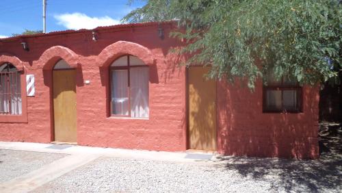 圣佩德罗·德·阿塔卡马Hostal Las Kañas的红砖建筑,有两扇门,有一棵树