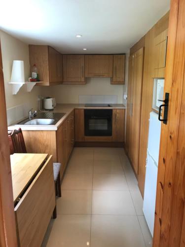 阿基尔High Road Cottage的厨房配有木制橱柜和白色冰箱。