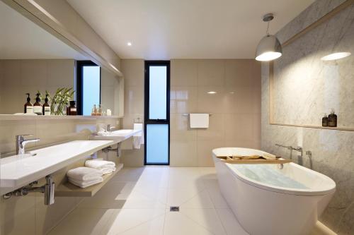 福林德斯弗林德斯酒店的白色的浴室设有2个盥洗盆和1个浴缸。