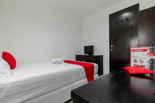 雅加达帕萨巴鲁红门优质旅馆的一间设有一张床和一张桌子及红毯的房间