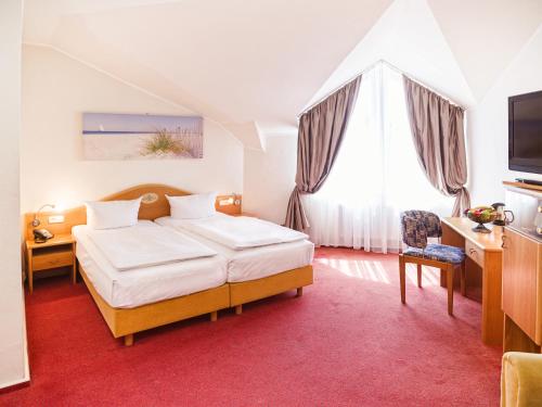 阿尔滕霍尔茨阿尔滕霍尔茨丹尼彻霍夫郁金香酒店的一间卧室配有一张床、一张书桌和一台电视