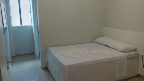 阿拉皮拉卡Hotel Confiança的客房内的一张带两个枕头的白色床