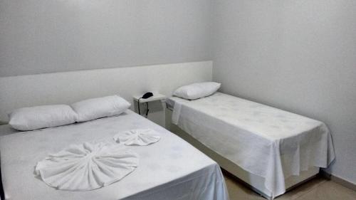 阿拉皮拉卡Hotel Confiança的一间设有两张带白色床单的床的房间