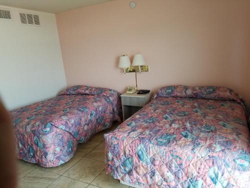 怀尔德伍德海滩露台汽车旅馆的酒店客房设有两张床和一张带台灯的桌子。