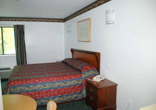 马纳萨斯时尚之家旅馆的一间卧室配有一张床和一张桌子及电话