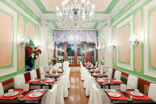 威尼斯德埃珀卡圣卡希亚诺酒店的一间带桌子、白色椅子和吊灯的用餐室