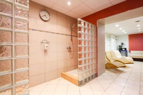 Vodňany普拉亚酒店的带淋浴的浴室和墙上的时钟