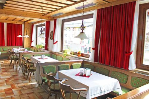 上陶恩Hotel Bella的一间带桌椅和红色窗帘的餐厅