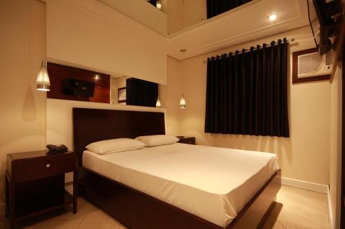 圣保罗Motel Atos ADULTS ONLY的卧室配有一张白色的大床和床头柜。