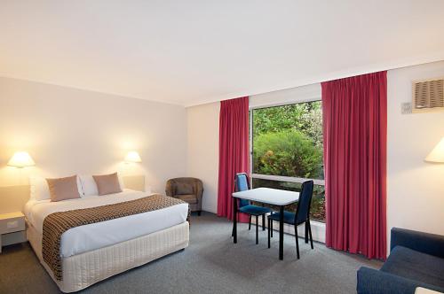 令伍特林伍德湖酒店的酒店客房设有床、桌子和窗户。