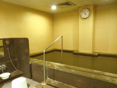古尔冈Dia Park Premier的一间带浴缸的浴室和墙上的时钟