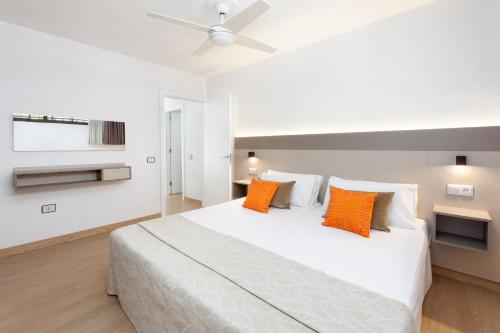 洛斯克里斯蒂亚诺斯Aguamar Apartamentos, Los Cristianos Downtown的卧室配有带橙色枕头的大型白色床