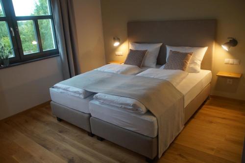 莱尔贝格Hotel Dorfmühle的卧室配有一张带白色床单和枕头的大床。