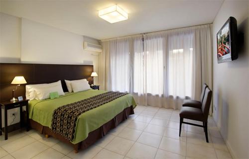 布宜诺斯艾利斯皮卡路加公寓酒店的卧室配有床、椅子和窗户。
