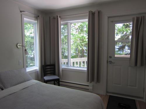 翁弗勒Auberge Île du Repos的一间卧室设有2扇窗户和1张床及椅子