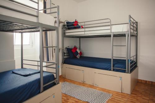 拉戈斯Orange3 Hostel的一间卧室配有两张双层床,铺有蓝色床单。
