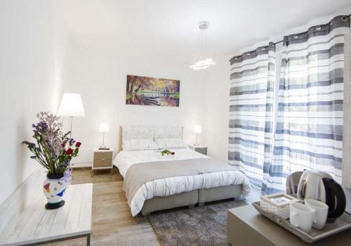 韦尔巴尼亚B&B Stella Maggiore的一间白色的卧室,配有一张床和花瓶