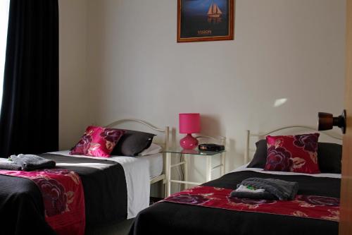 开普敦杰维斯凯普杰维斯度假屋的一间设有两张床和粉红色灯的房间