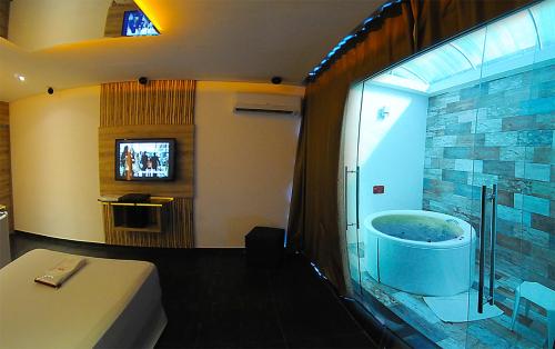 累西腓Eros Hotel CDU (Adults Only)的一间带浴缸的浴室和一台电视。