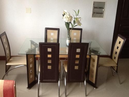 圣多美E格拉瓦那公寓的一个带椅子的玻璃桌和一个花瓶
