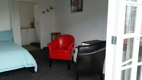 芒格努伊山Mauao Studio的一间卧室配有红色椅子和一张床