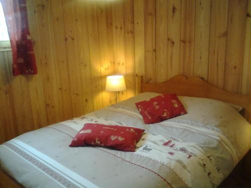 布里昂松Le chalet的一间卧室配有一张带两个红色枕头的床