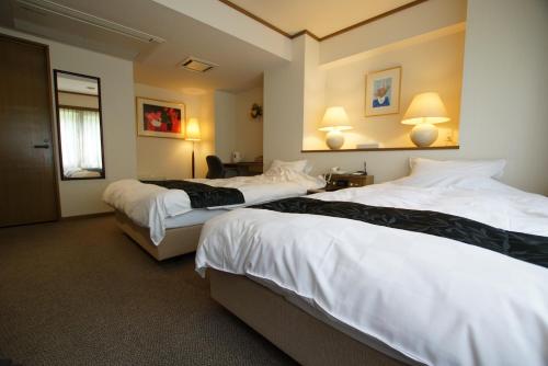 丰冈市翠山庄日式旅馆的酒店客房设有两张床和两盏灯。