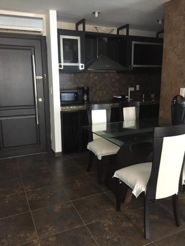 蓬塔布兰卡Punta Centinela Apartment的厨房配有黑桌和白色椅子