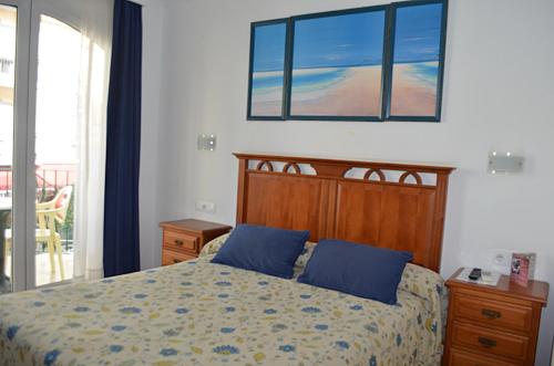 多列毛利诺斯普拉萨玛尔公寓的一间卧室配有一张带蓝色枕头的床