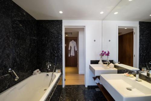 海若克利欧拉奎拉亚特兰蒂斯酒店的浴室配有2个盥洗盆、浴缸和浴缸。