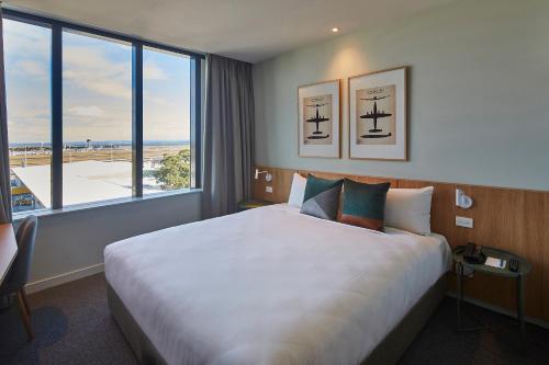 悉尼悉尼机场曼特拉酒店的一间酒店客房,设有一张大床和一个大窗户