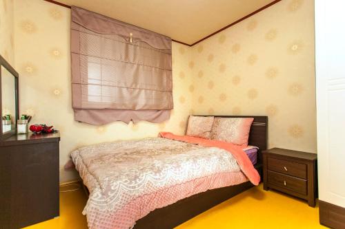 西归浦市努扬那阳度假屋的一间卧室配有一张床、一个梳妆台和一扇窗户。