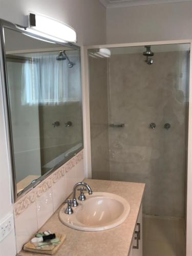 阿波罗湾海浪汽车旅馆&公寓的浴室配有盥洗盆和带镜子的淋浴