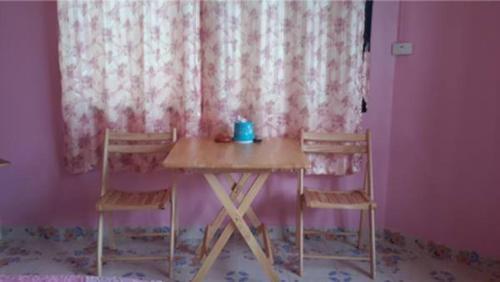 夜功府Royal Land Mae Klong Hotel的一张桌子和两把椅子,放在带窗帘的房间