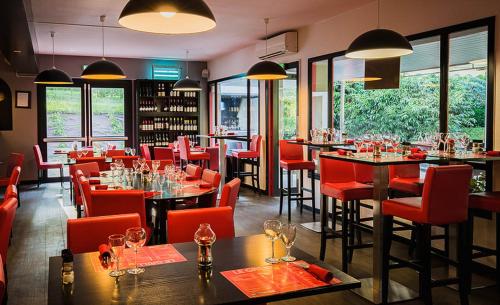 隆勒索涅隆勒索涅乐吉斯酒店 - 烧烤餐厅的餐厅设有红色的椅子和桌子以及窗户。