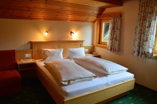 拉姆绍达赫斯坦Pension Trillerhof的一间卧室配有一张带白色床单的床和一扇窗户。