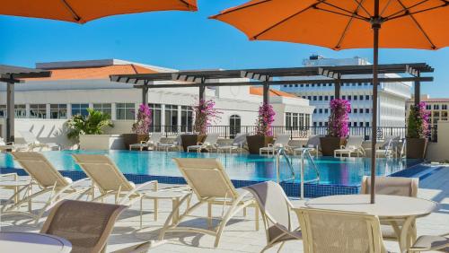 布卡拉顿博卡拉顿凯悦嘉轩酒店的一个带桌椅和遮阳伞的游泳池